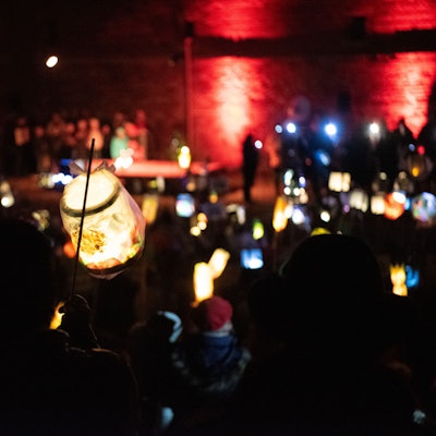 Eine Laterne wird vor der Zülpicher Burg hochgehalten, im Hintergrund leuchten noch mehr Laternen.