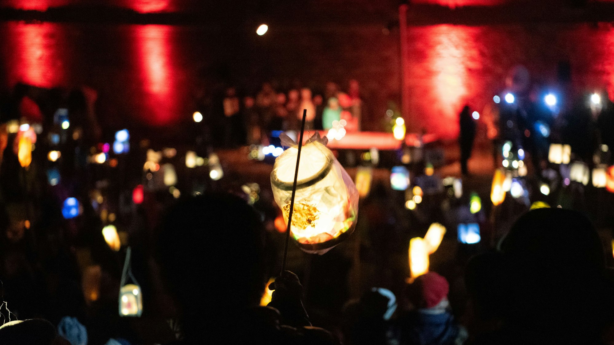 Eine Laterne wird vor der Zülpicher Burg hochgehalten, im Hintergrund leuchten noch mehr Laternen.