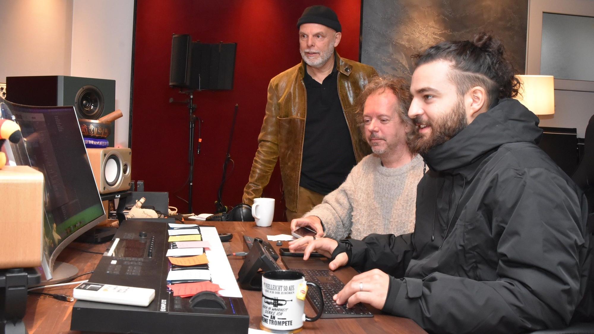 Drei Männer arbeiten am Mischpult in einem Tonstudio.