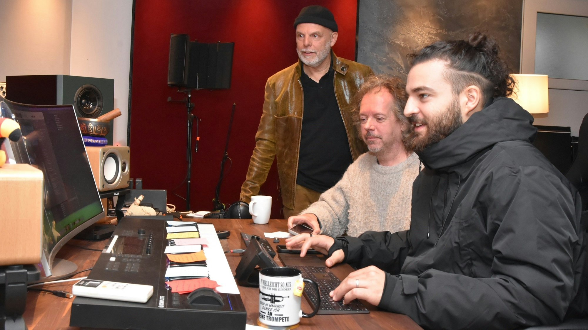 Drei Männer arbeiten am Mischpult in einem Tonstudio.