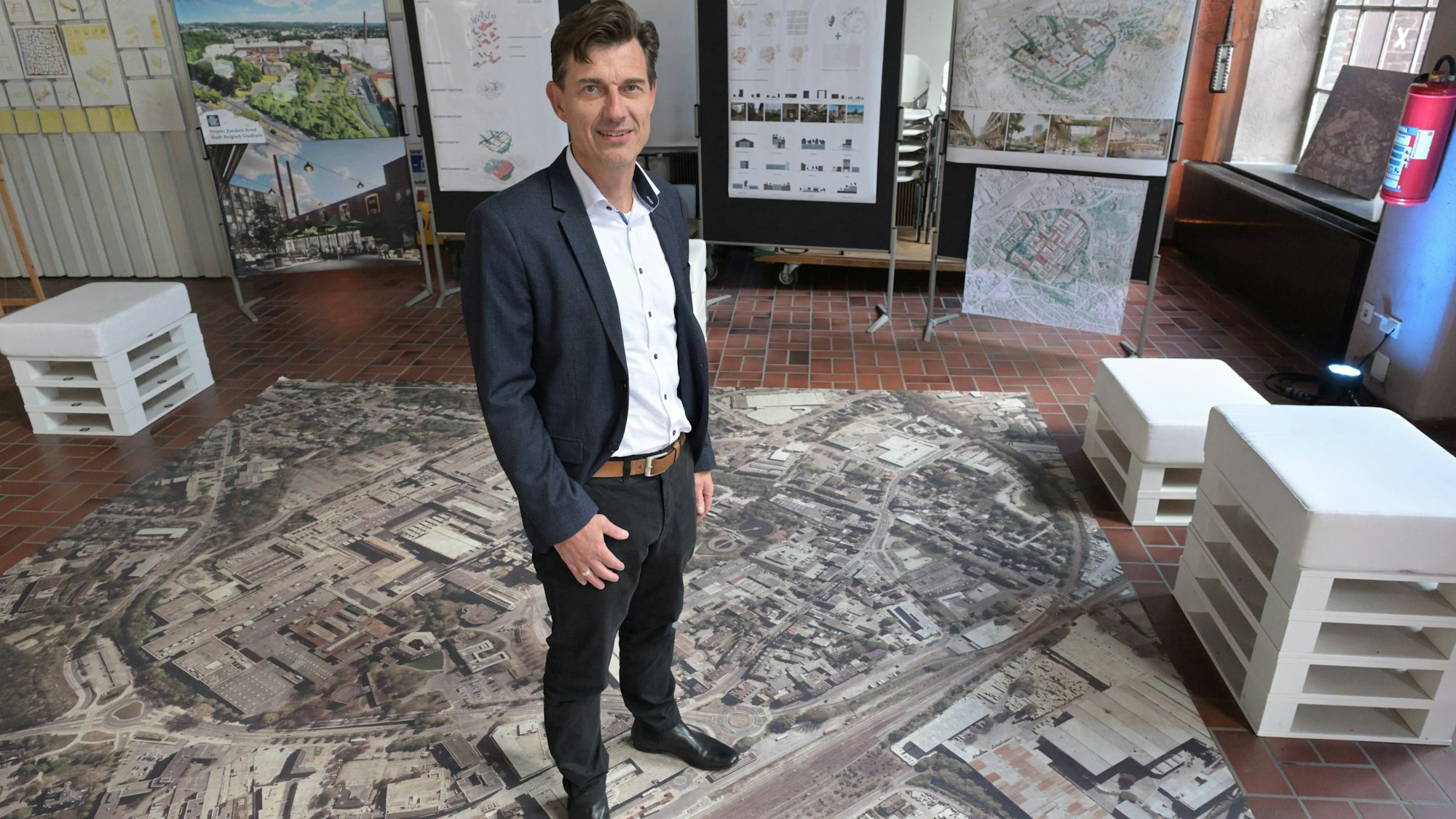 Oliver Brügge bei seiner Vorstellung im Oktober 2024. Er steht auf einem Foto der  36 Hektar großen Industriebrache.