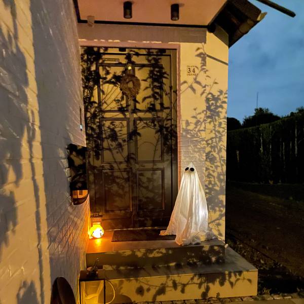 Vor einem Hauseingang steht ein leuchtender Geist als Halloween-Dekoration.