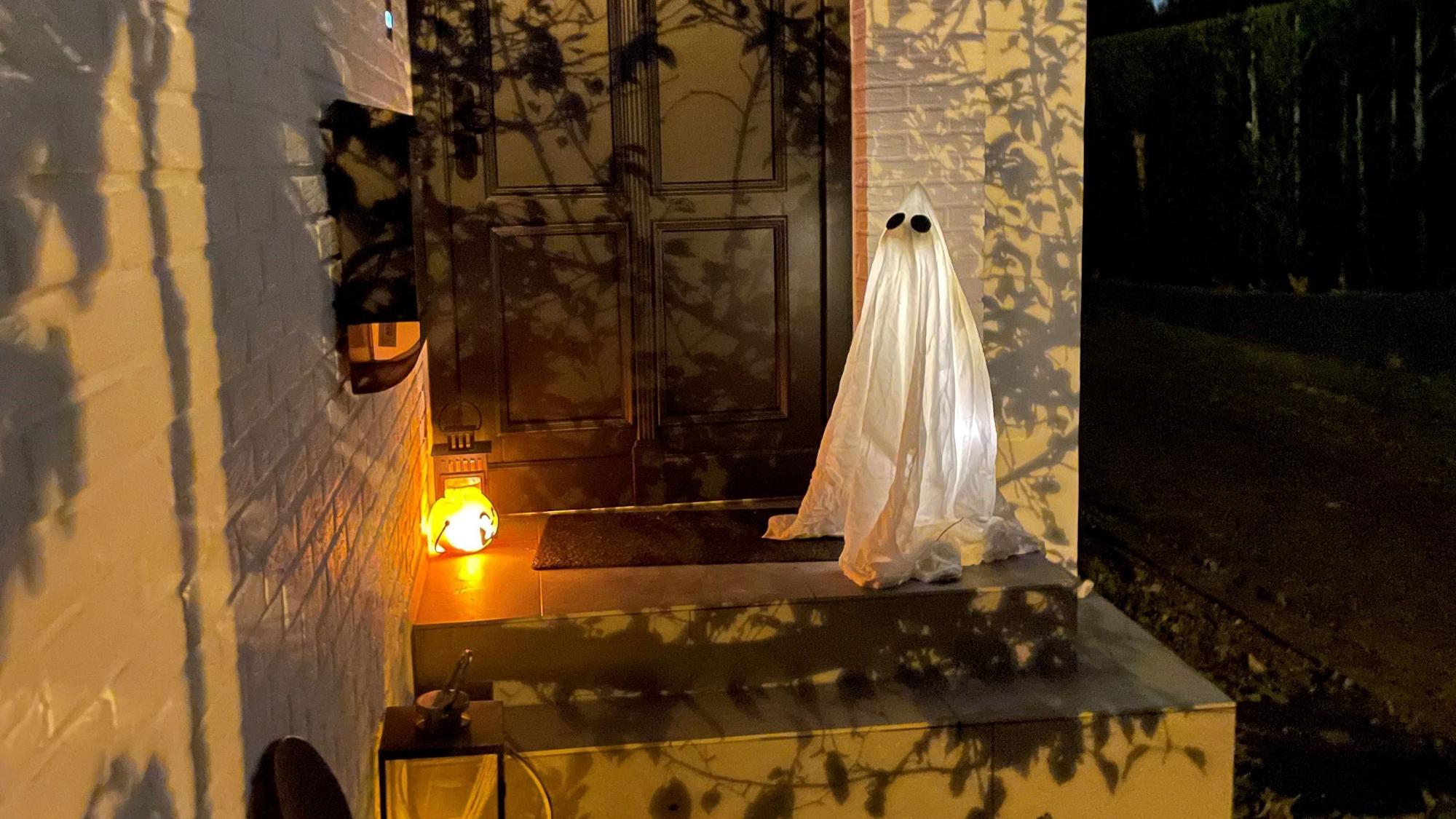 Vor einem Hauseingang steht ein leuchtender Geist als Halloween-Dekoration.