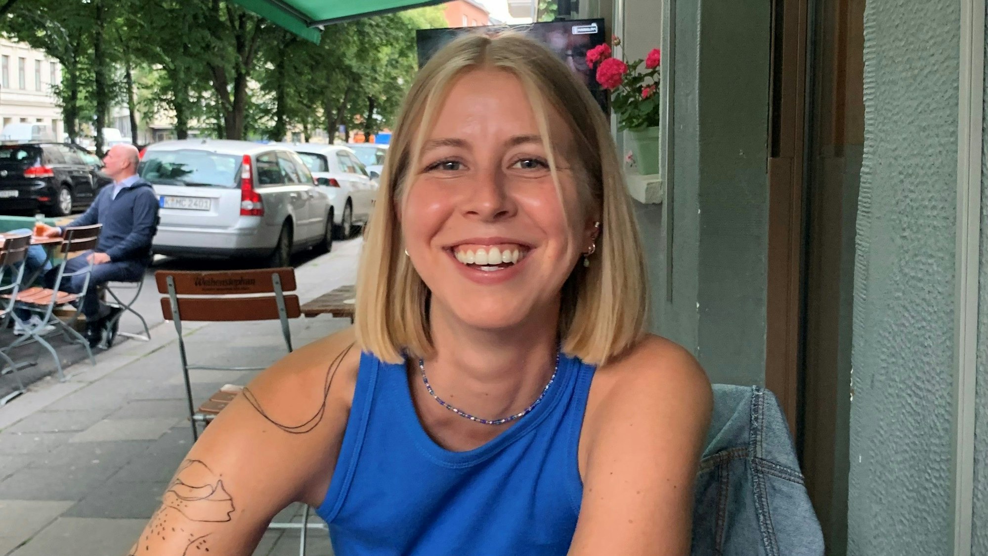 Eine Frau sitzt an einem Tisch an einer Straße.