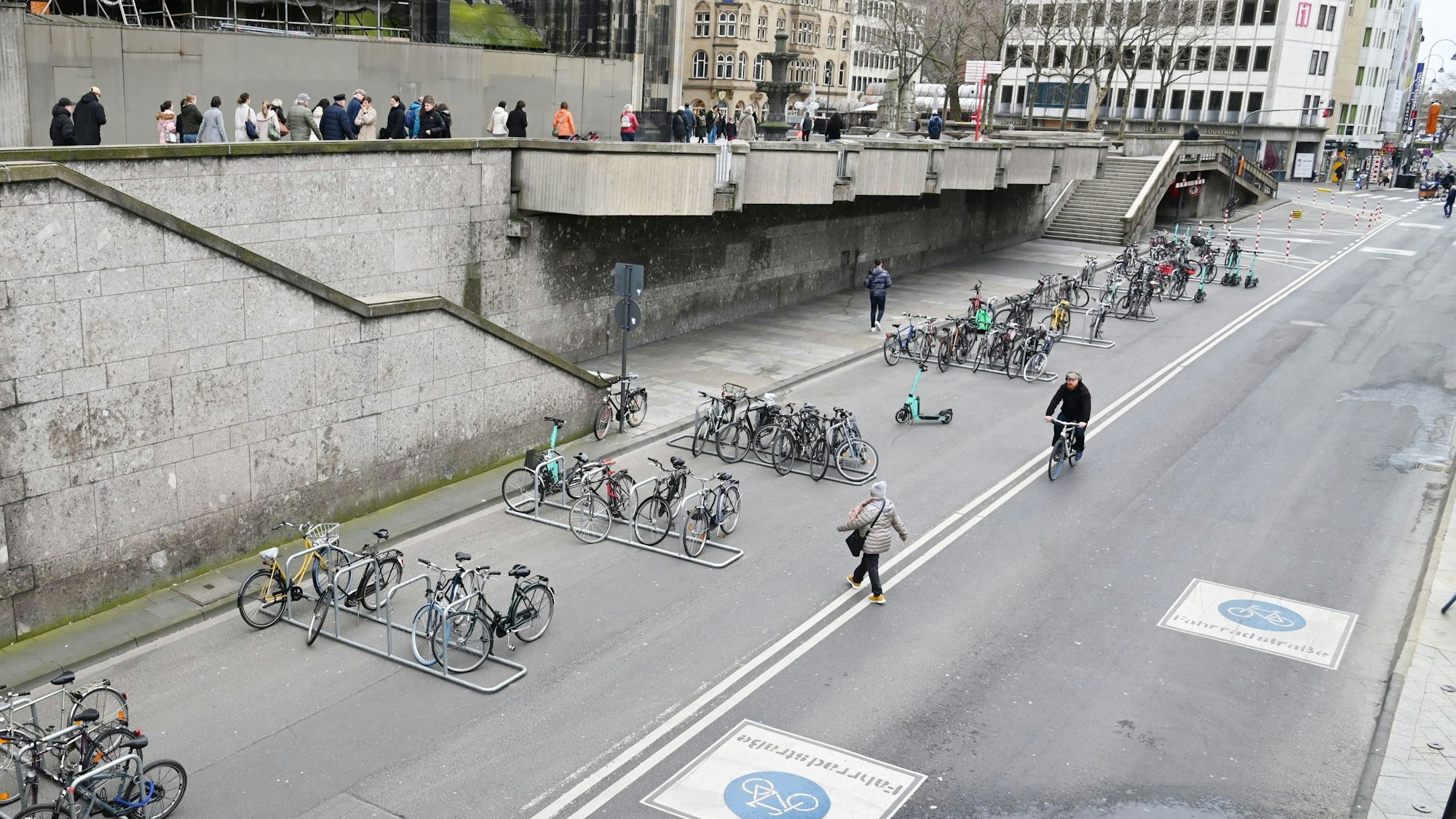 Auf der zur Fahrradstraße umgewidmetenTrankgasse direkt an der Domplatte hat die Stadt Köln zahlreiche Fahrradständer aufgebaut. Die oben im Bild zu sehenden Passanten können dort zukünftig für einige Zeit nicht mehr entlang gehen.