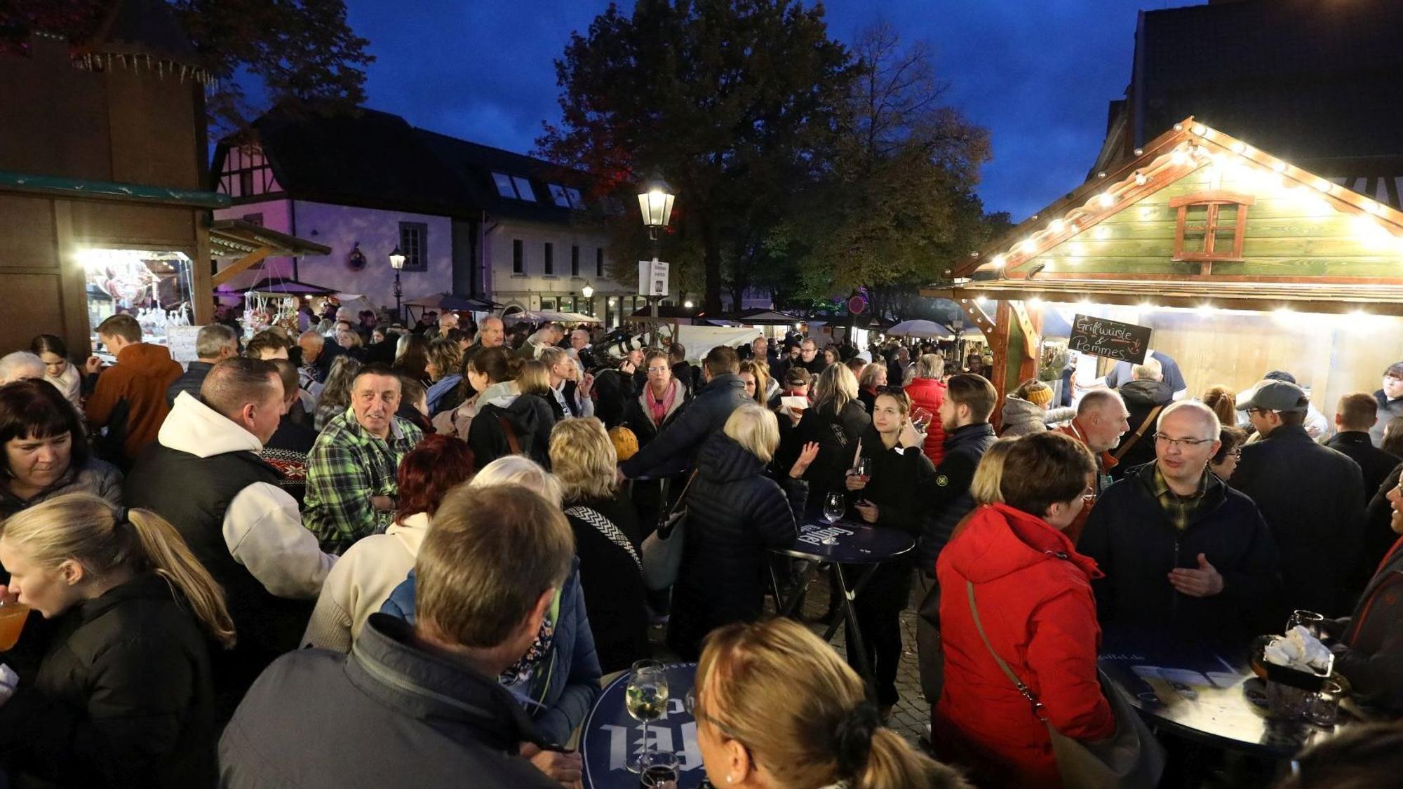 Zahlreiche Menschen stehen eng zusammen an und vor den Buden des Martini Marktes.
