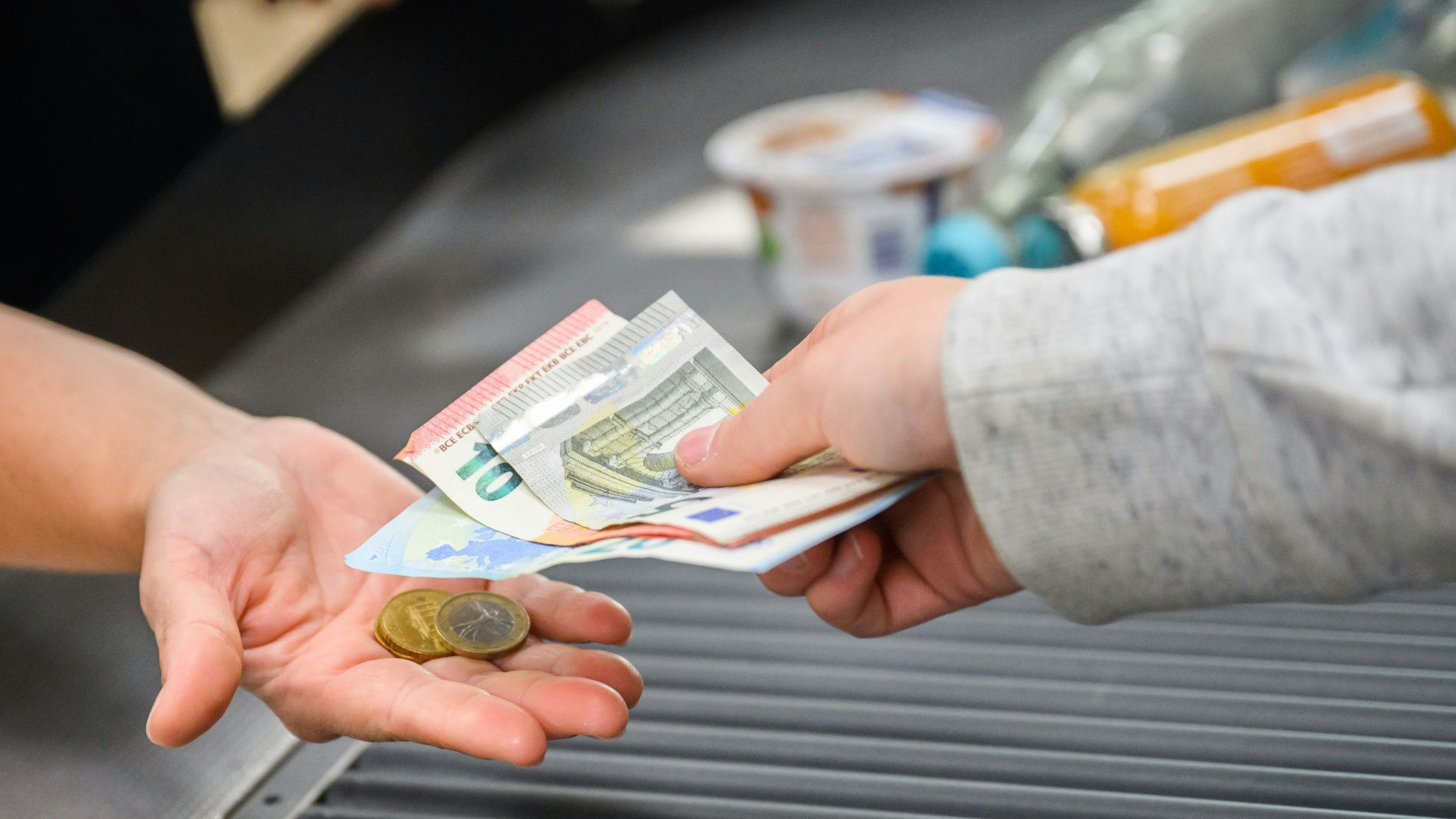 Eine Kassiererin gibt einer Kundin Wechselgeld an der Kasse eines Supermarktes.