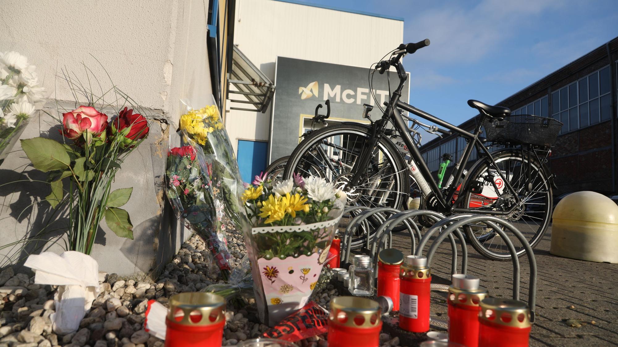 Blumen und Kerzen erinnern einen Tag später an den tödlichen Schuss, den ein Unbekannter auf einen 32-Jährigen vor dem Fitnessstudio in Köln-Kalk abgefeuert hat.