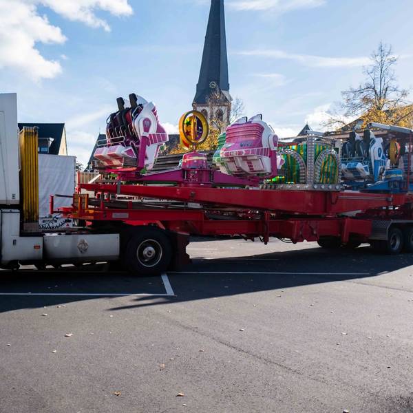 Ein Lastwagen mit einem Fahrgeschäft fährt auf den Kirmesplatz in Euskirchen.