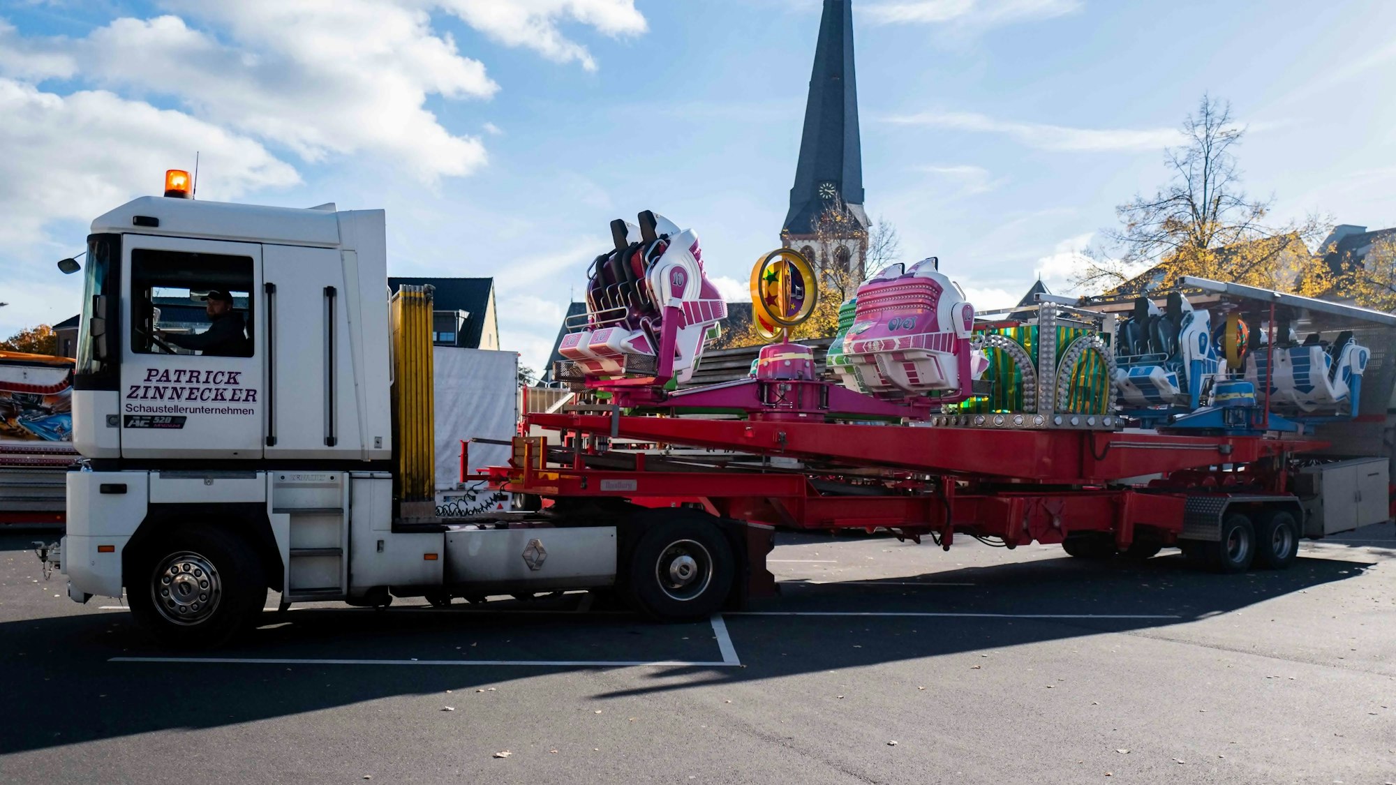 Ein Lastwagen mit einem Fahrgeschäft fährt auf den Kirmesplatz in Euskirchen.