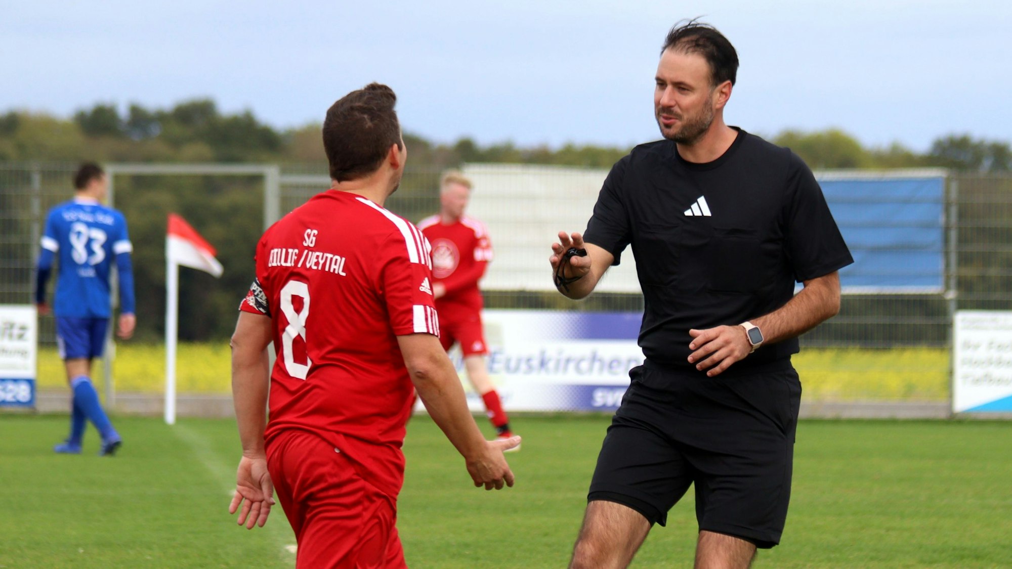 Ein Schiedsrichter mit freundlichem Gesicht redet mit einem Spieler.