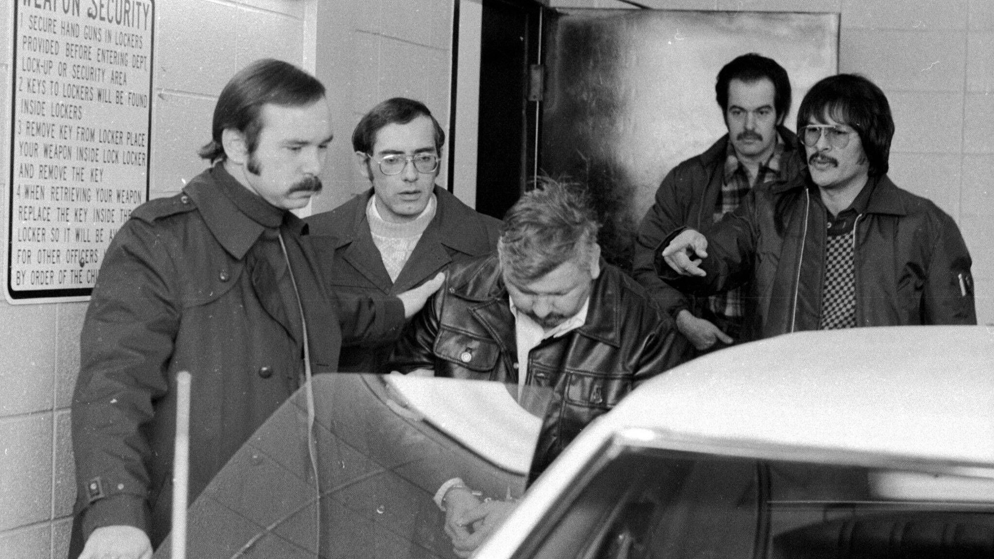 Der damals 36-jährige John Wayne Gacy wird aus dem Polizeirevier von Des Plaines auf dem Weg in ein Krankenhaus abgeführt.