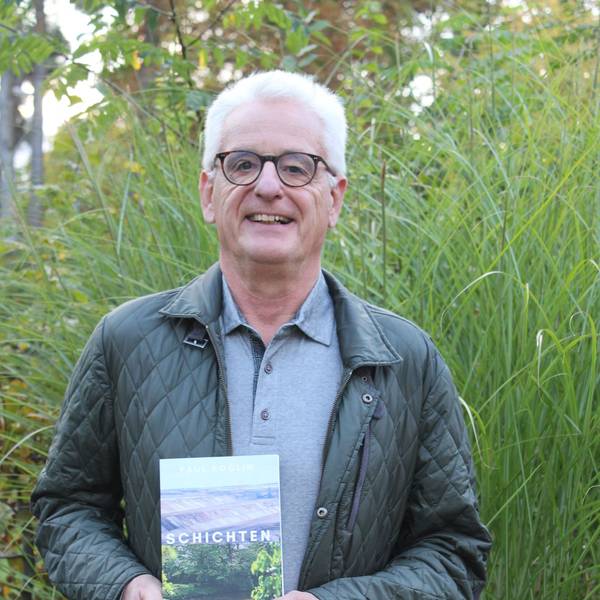 Der Autor steht draußen in der freien Natur, hinter ihm wächst hohes Gras.