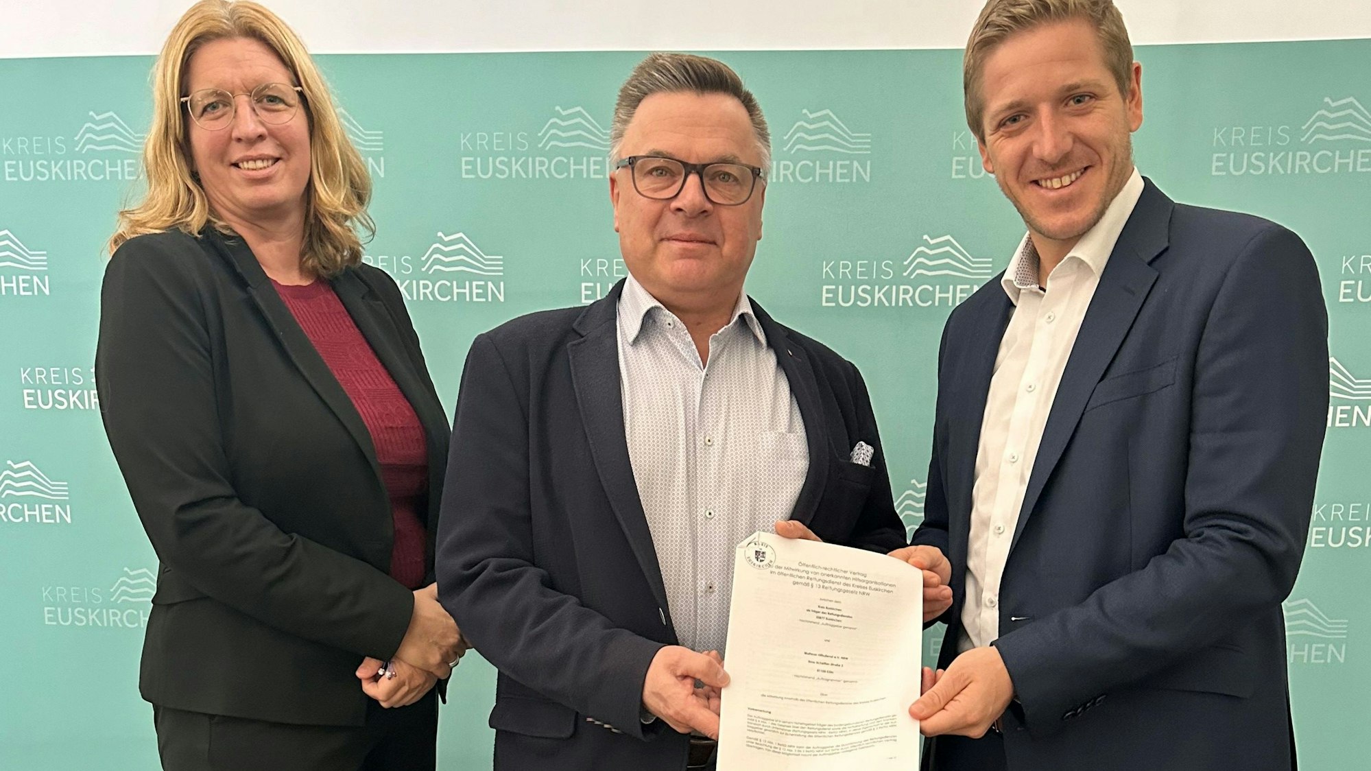Das Bild zeigt die Julia Baron, Michael Krämer und Markus Ramers, wie sie den unterschriebenen Vertrag präsentieren.