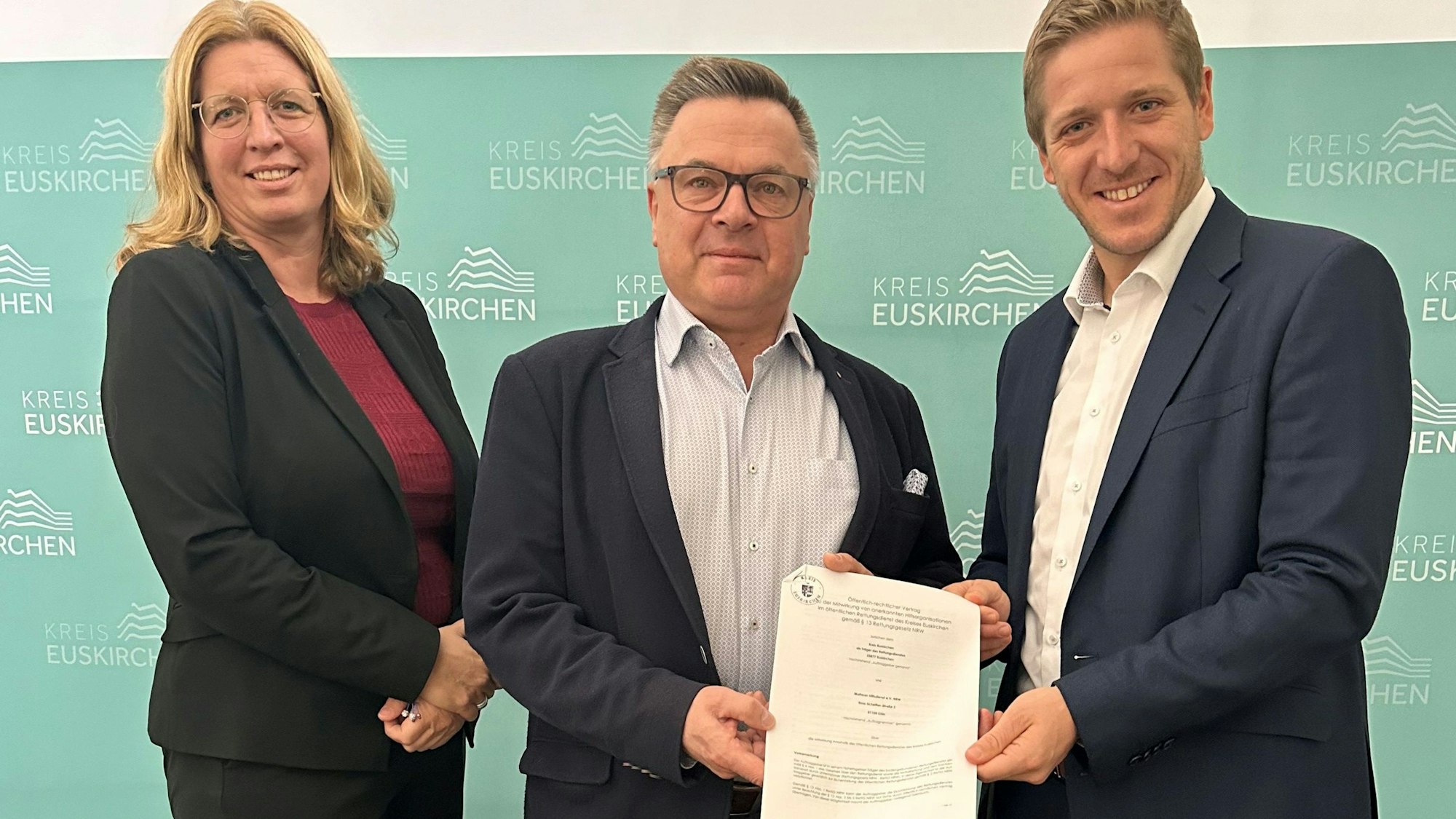 Das Bild zeigt die Julia Baron, Michael Krämer und Markus Ramers, wie sie den unterschriebenen Vertrag präsentieren.