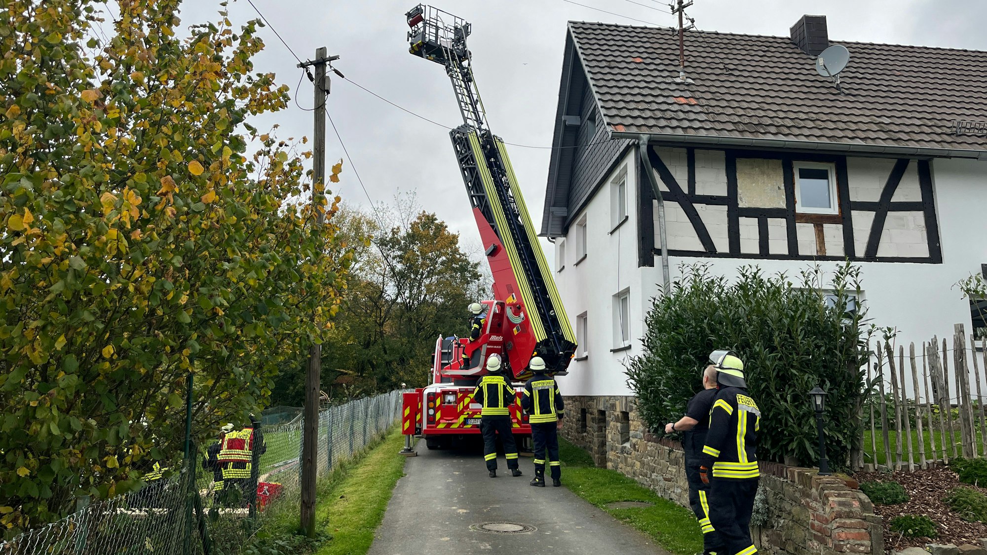 Eine Drehleiter steht in einer schmalen Gasse und schwenkt ihren Leiterpark.