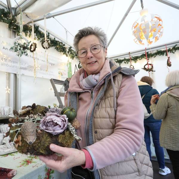 Eine Frau zeigt ein Blumengesteck.