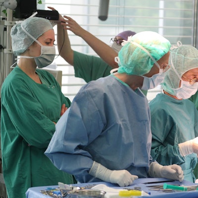 Mehrere Ärzte und Schwestern in Kitteln bei einem chirurgischen Eingriff.