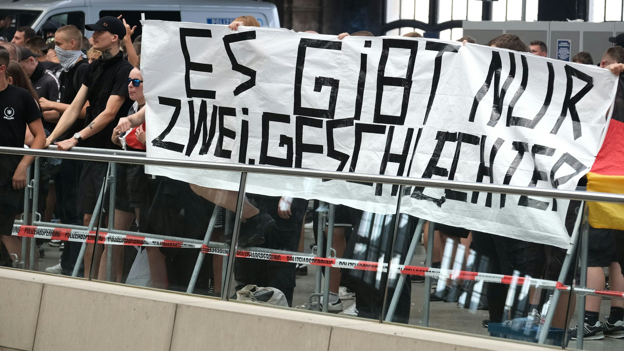 Teilnehmer einer rechtsextremen Versammlung halten im Hauptbahnhof Leipzig ein Transparent mit der Aufschrift „Es gibt nur zwei Geschlechter“ hoch.