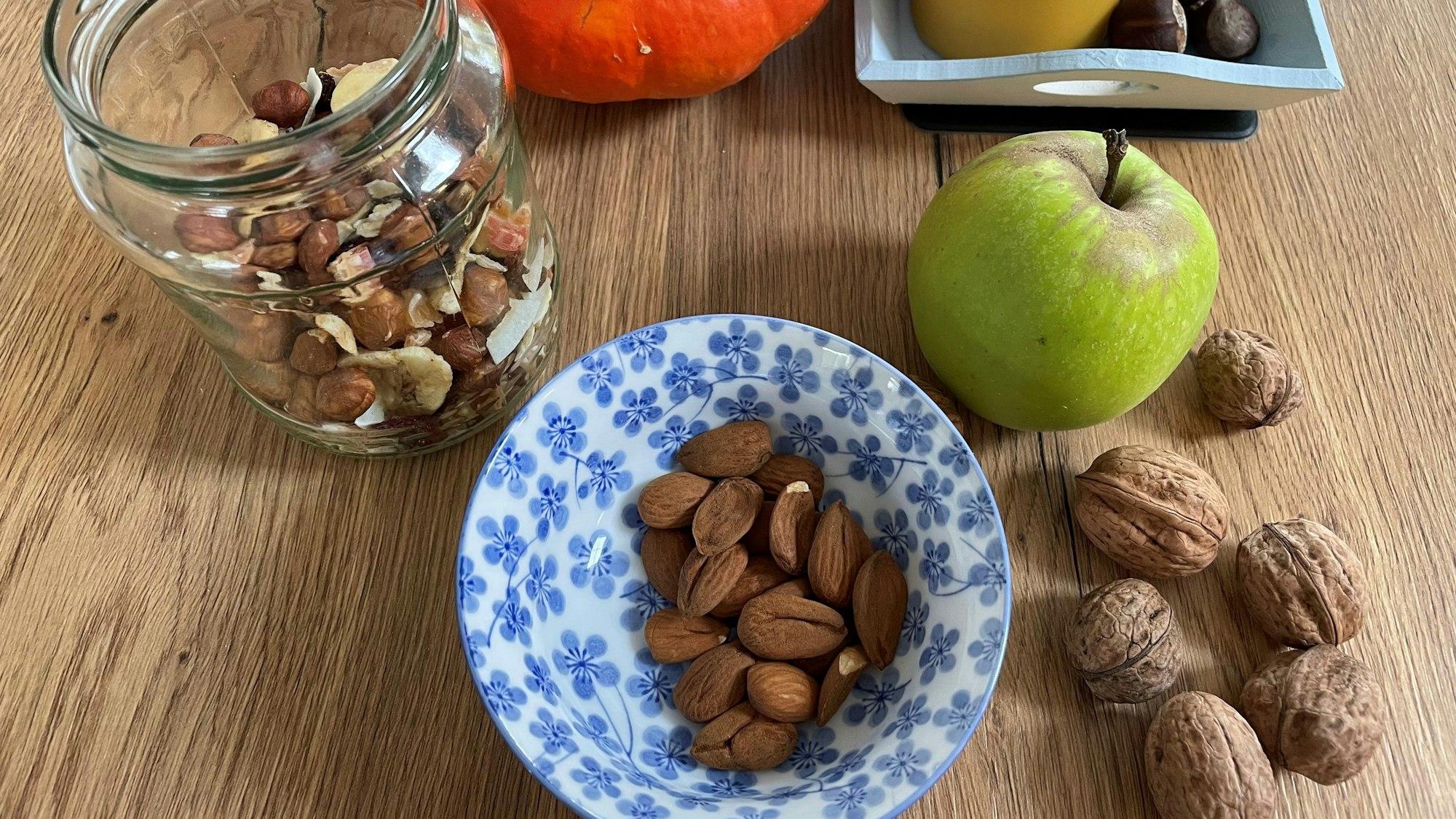 Gesunde Lebensmittel wie Nüsse und Studentenfutter liegen auf einem Tisch.