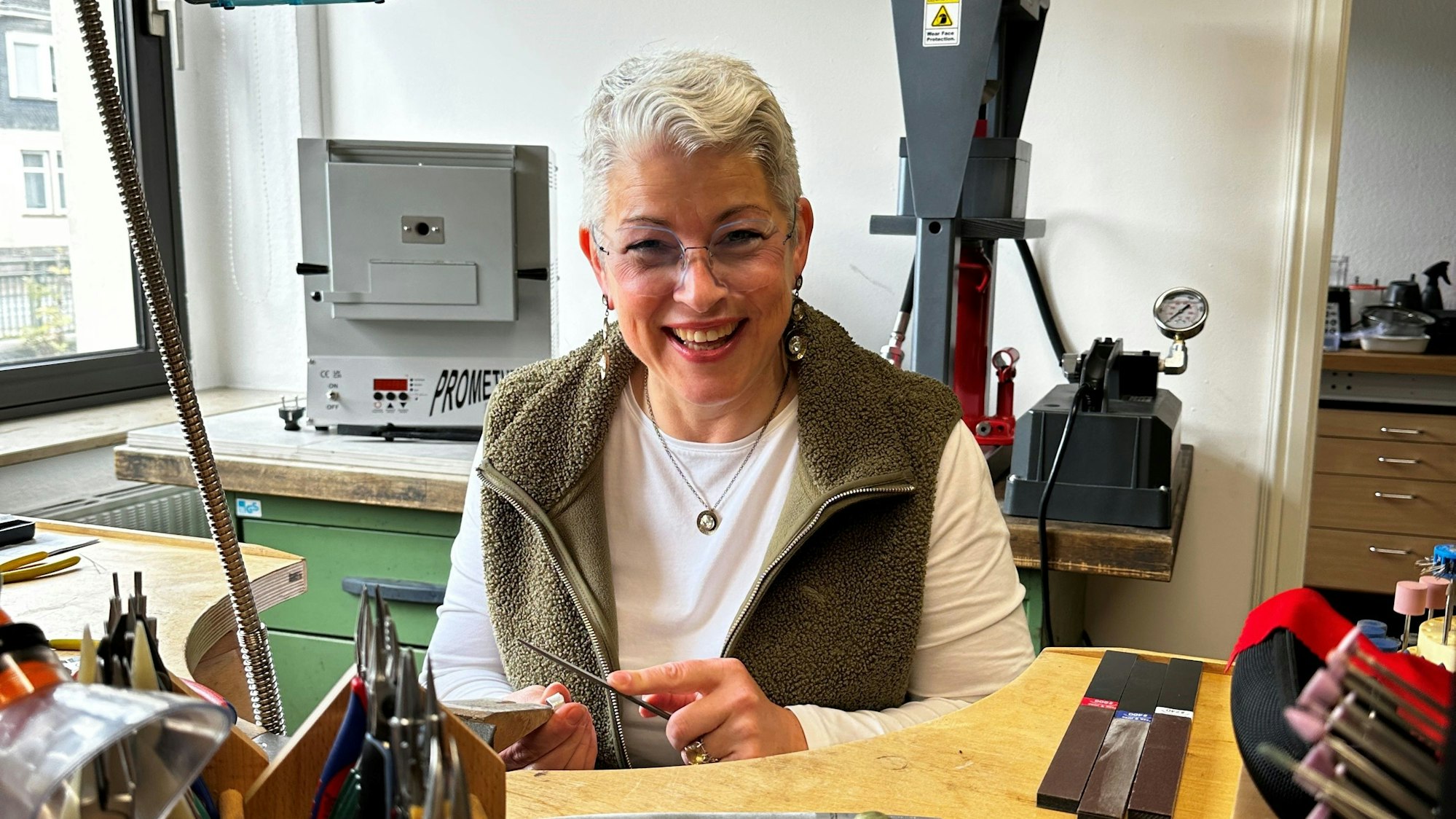 Angela Klussmann sitzt in ihrer Werkstatt, in der sie Schmuck herstellt.