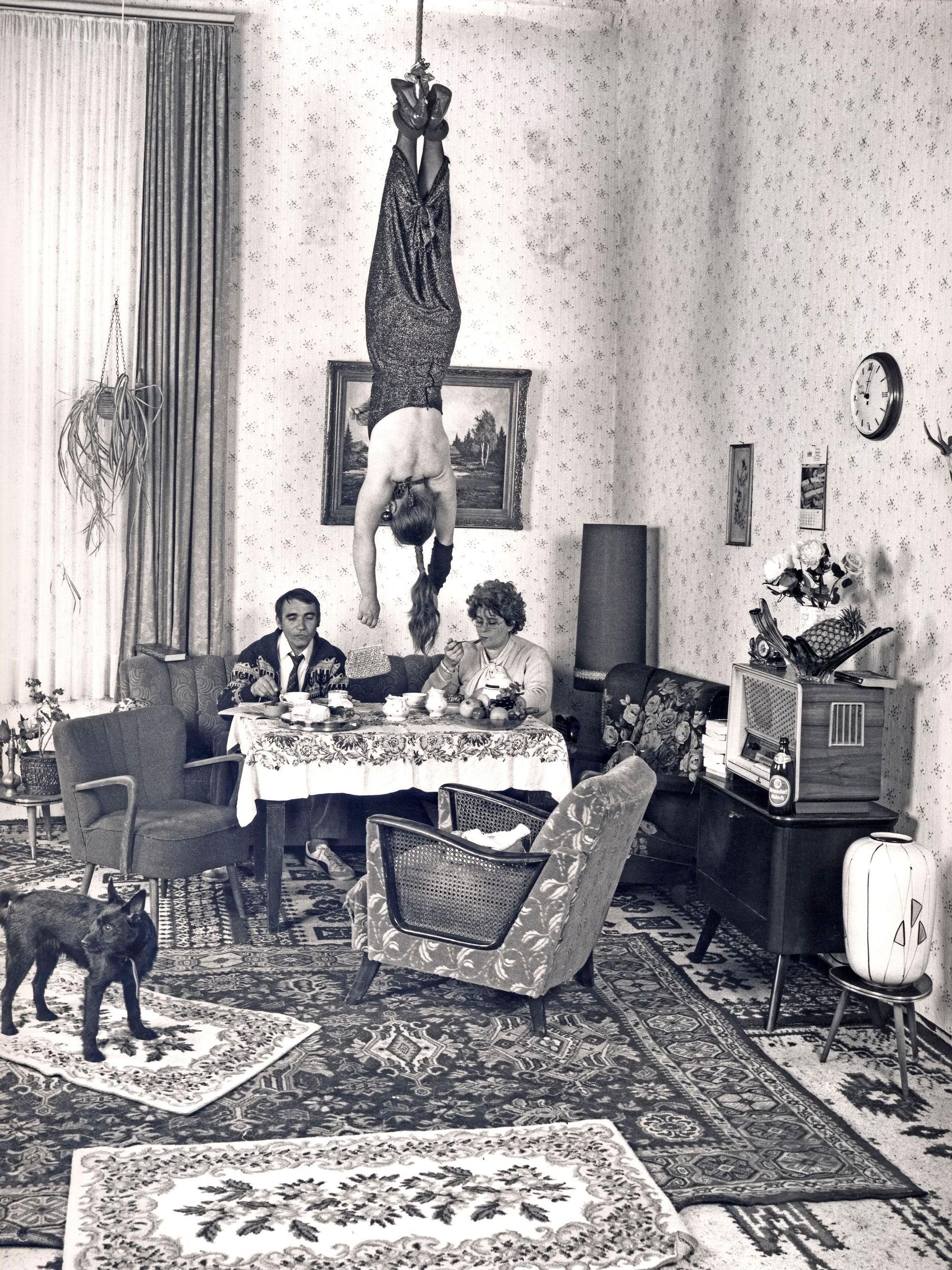 Eine Frau hängt in einem Wohnzimmer kopfüber von der Decke.