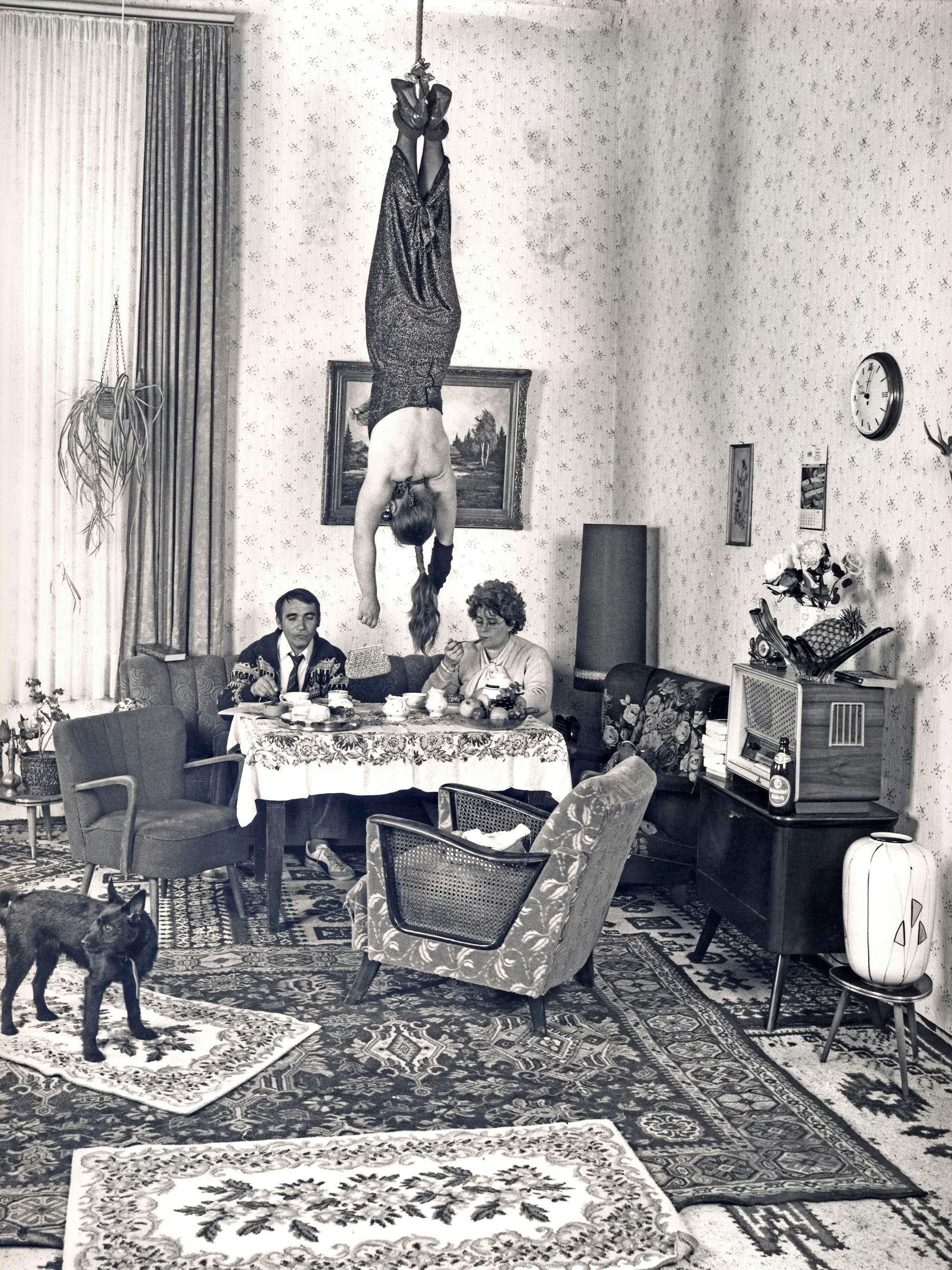 Eine Frau hängt in einem Wohnzimmer kopfüber von der Decke.