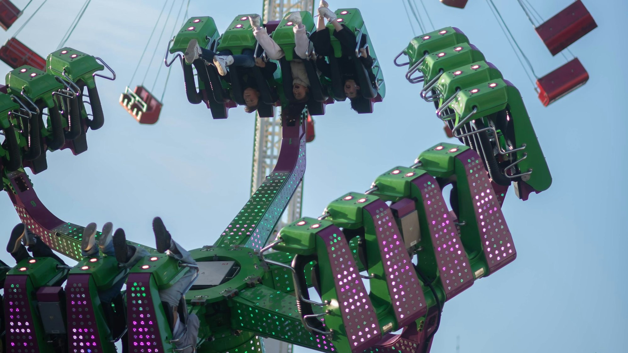 Menschen sitzen über Kopf in Sitzen eines Fahrgeschäfts.