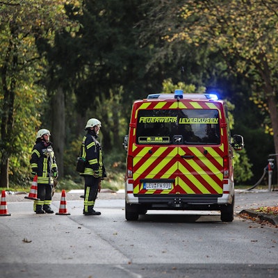 Zwei Feuerwehrleute stehen an einem Einsatzwagen.