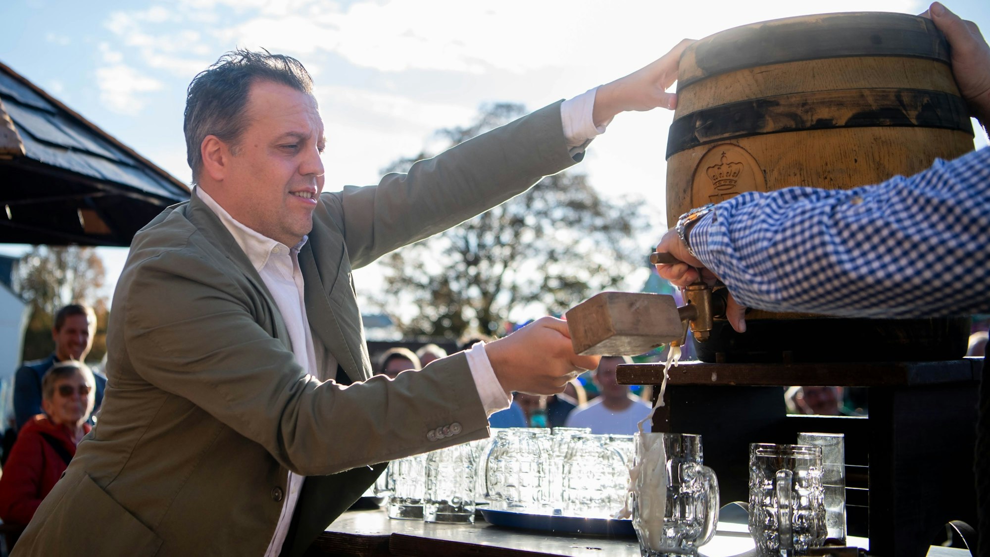 Ein Mann im Anzug sticht ein Fass an.