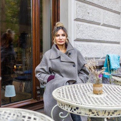 Eine Frau sitzt an einem Tisch vor einem Café.