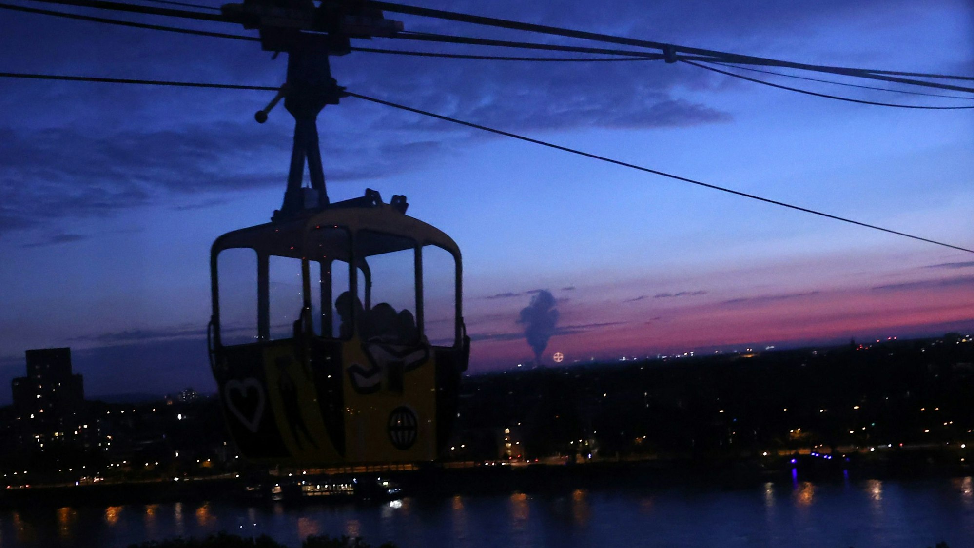 Kölner Seilbahn fährt durch späten Abendhimmel