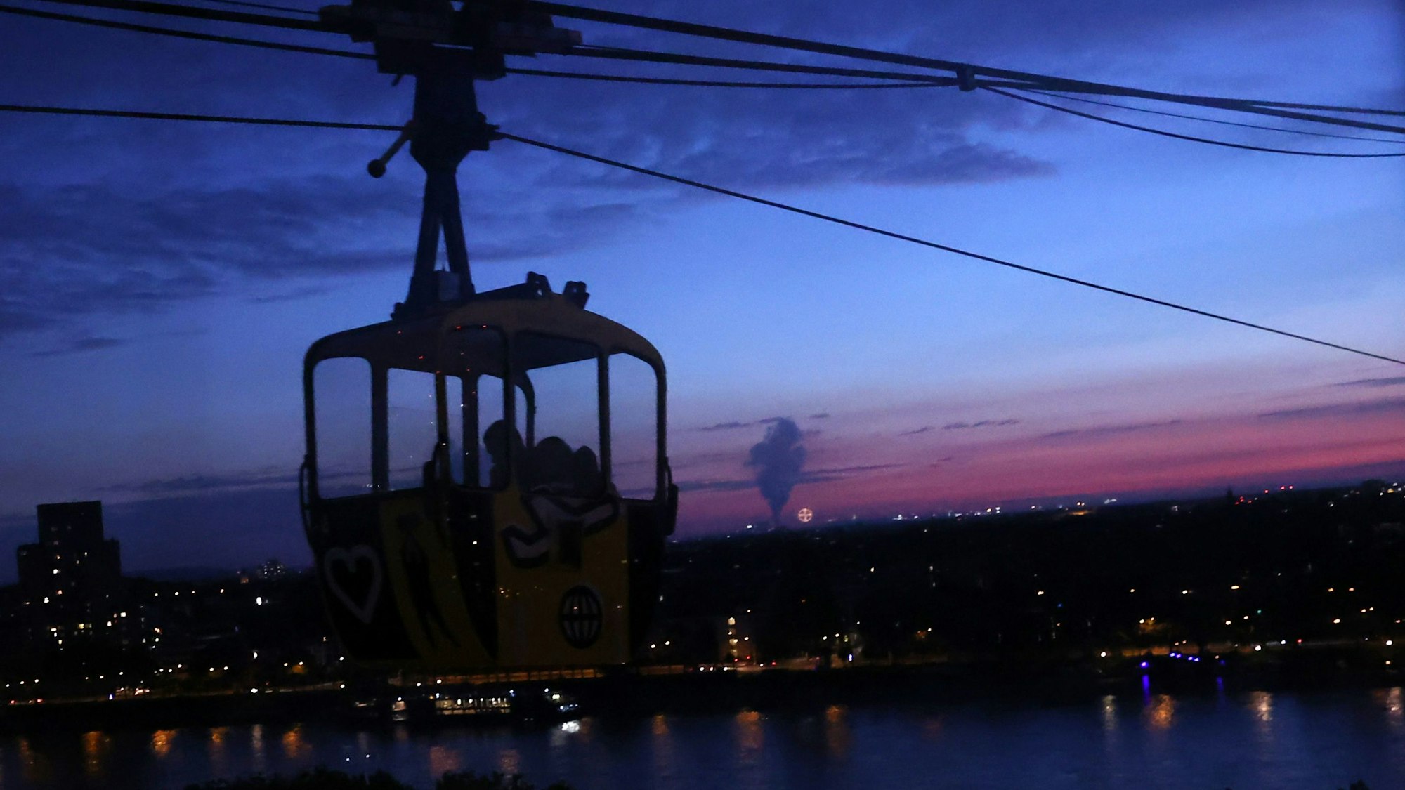 Kölner Seilbahn fährt durch späten Abendhimmel