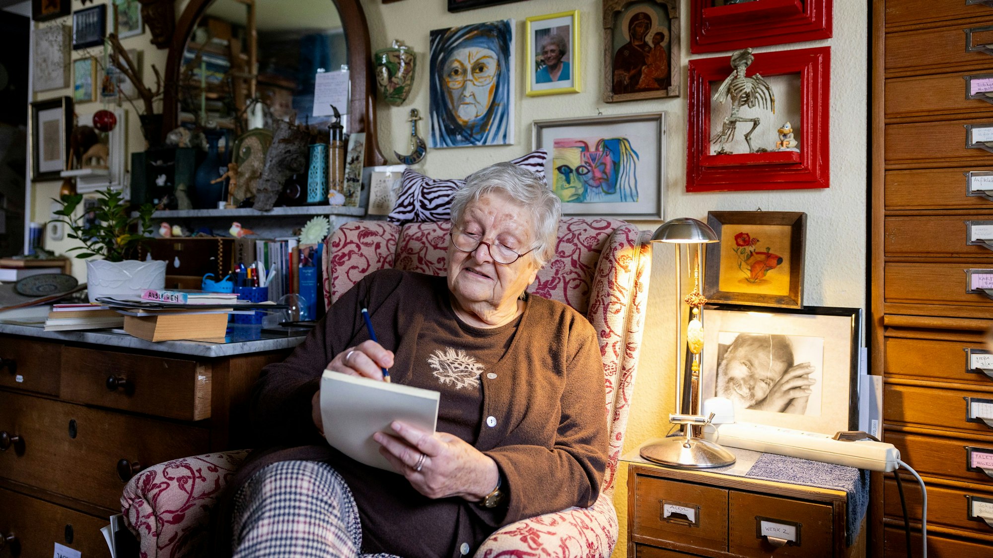 Eine von Behechti sitzt in einem Sessel und zeichnet etwas