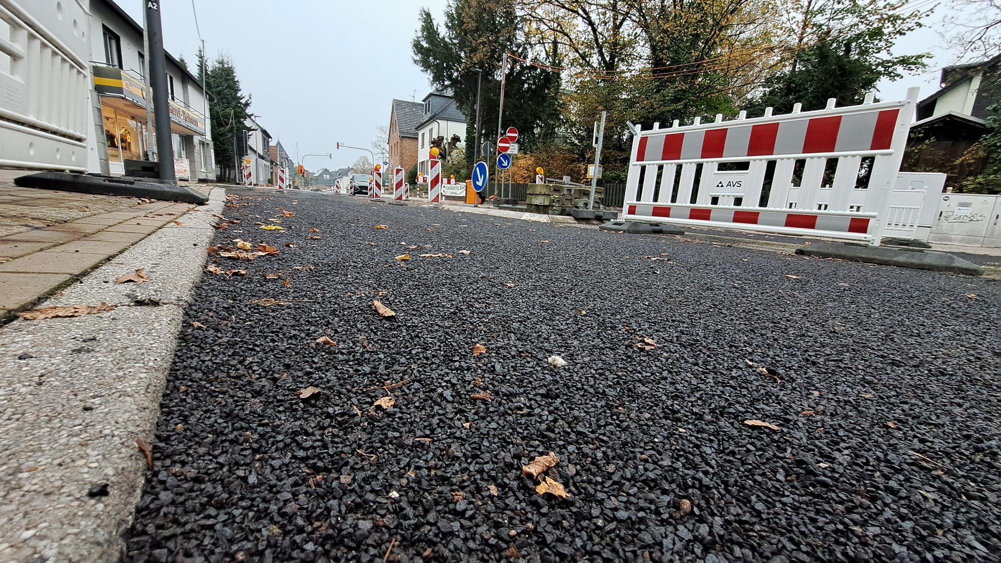 Aus der Froschperspektive ist die neue Asphaltschicht auf der Bensberger Straße in Overath-Heiligenhaus zu sehen.