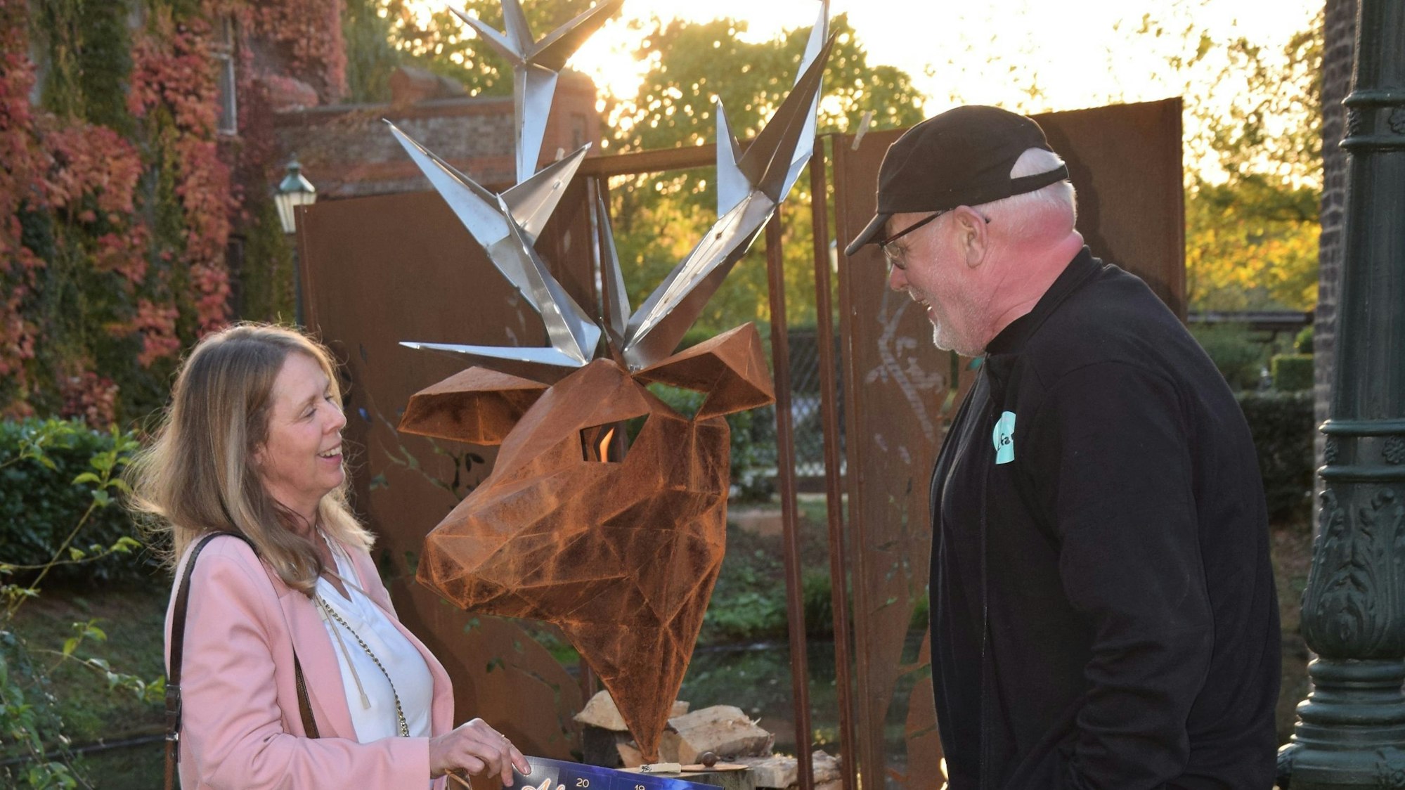Eine Frau und ein Mann stehen vor einem Paravent mit Hirschgeweih aus Cortenstahl-Objekte.