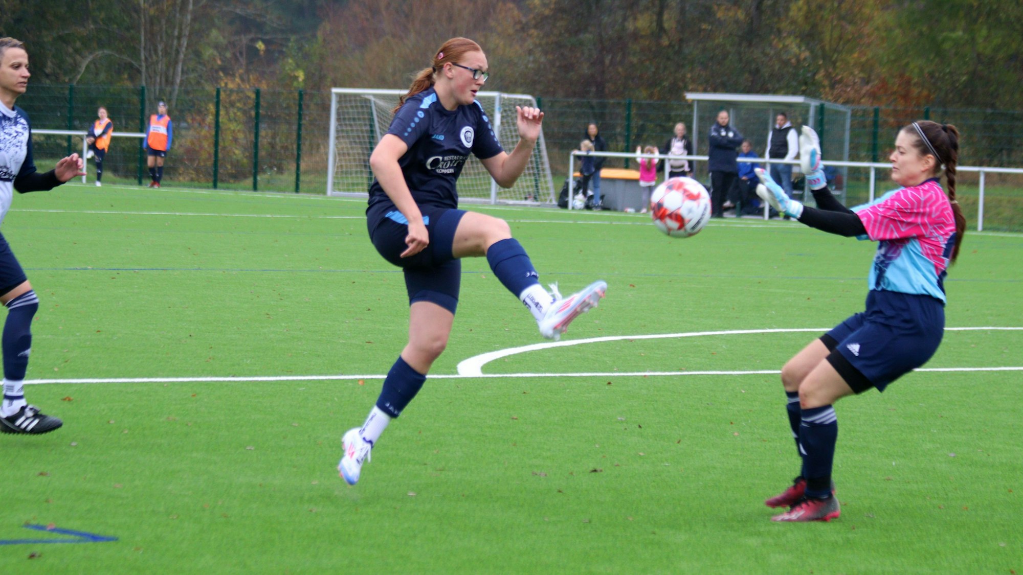 Eine Fußballerin chippt einen Ball über die herannahene Torhüterin.
