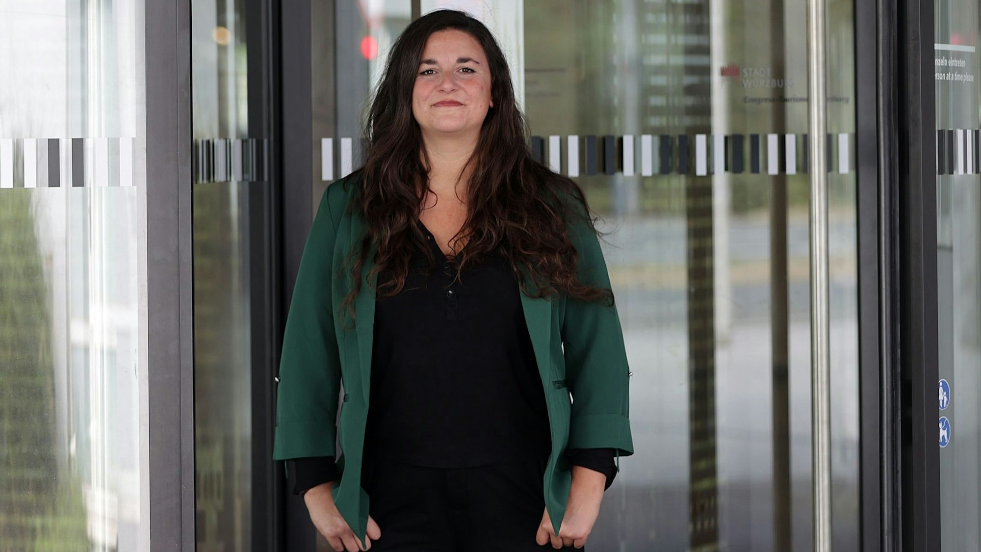 Eine Frau steht vor einer Glastür.