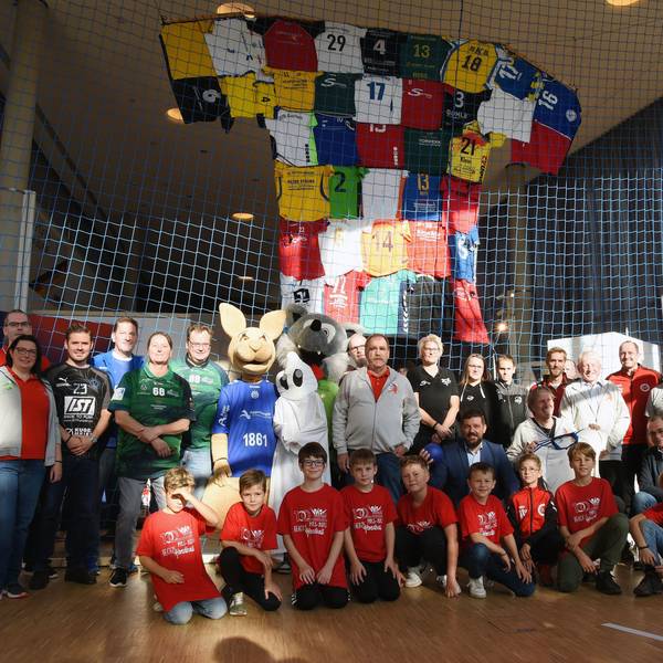 In einem Netz ist das große Trikot befestigt. Davor haben sich die Besucher der Ausstellung platziert.
