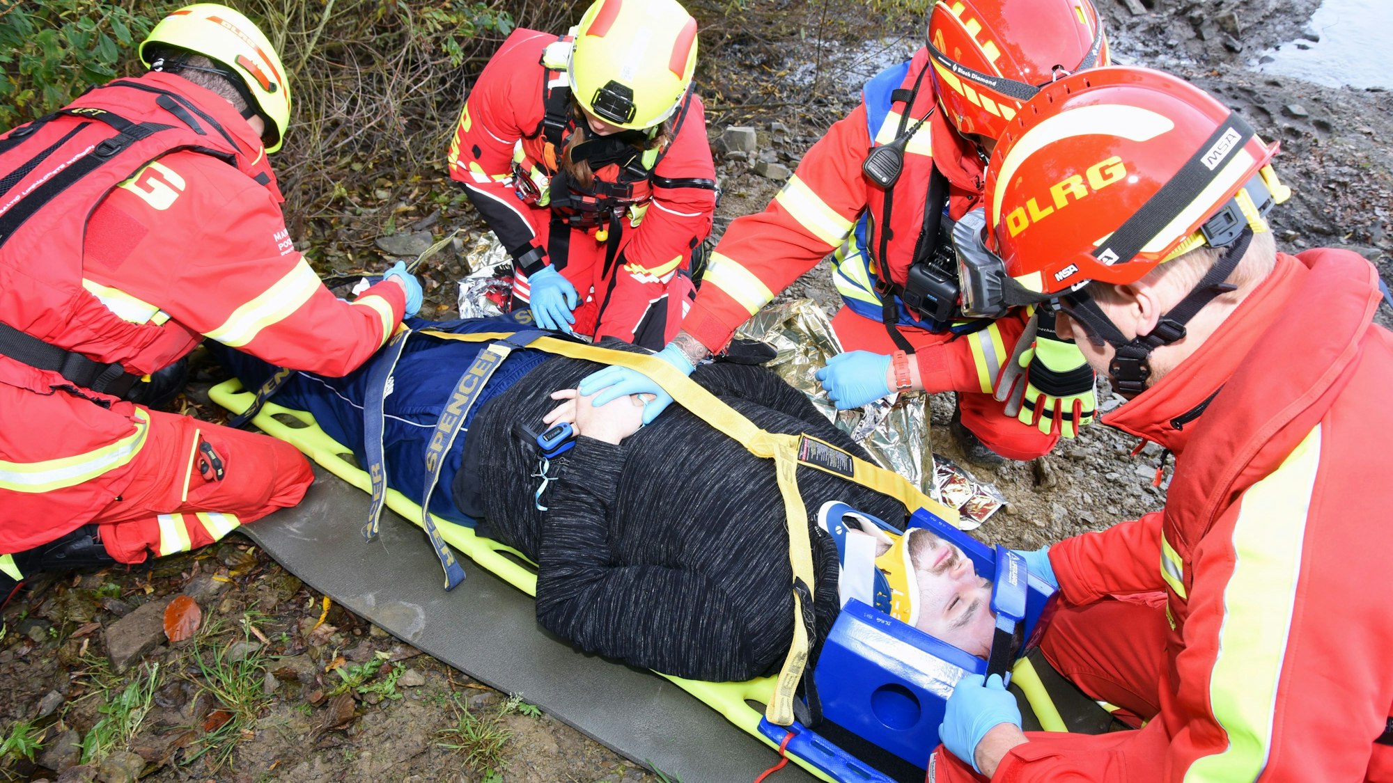 Ein Verletzter wird für den Transport mit dem Boot auf einer Trage fixiert.