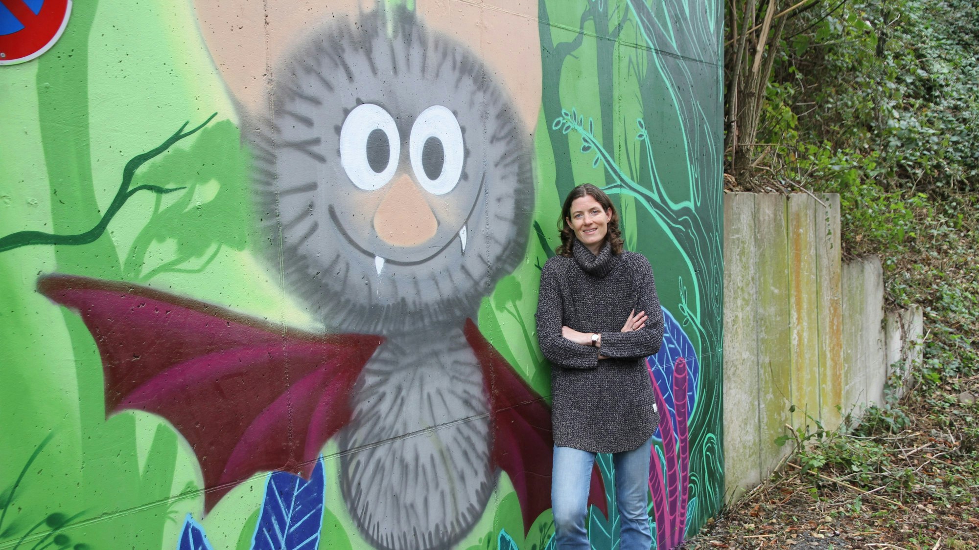 Eine Frau vor einem Graffiti mit einer Fledermaus.