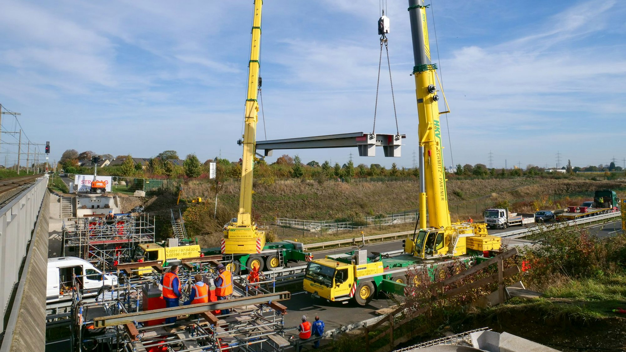 An zwei Kränen ist ein Brückenelement befestigt.