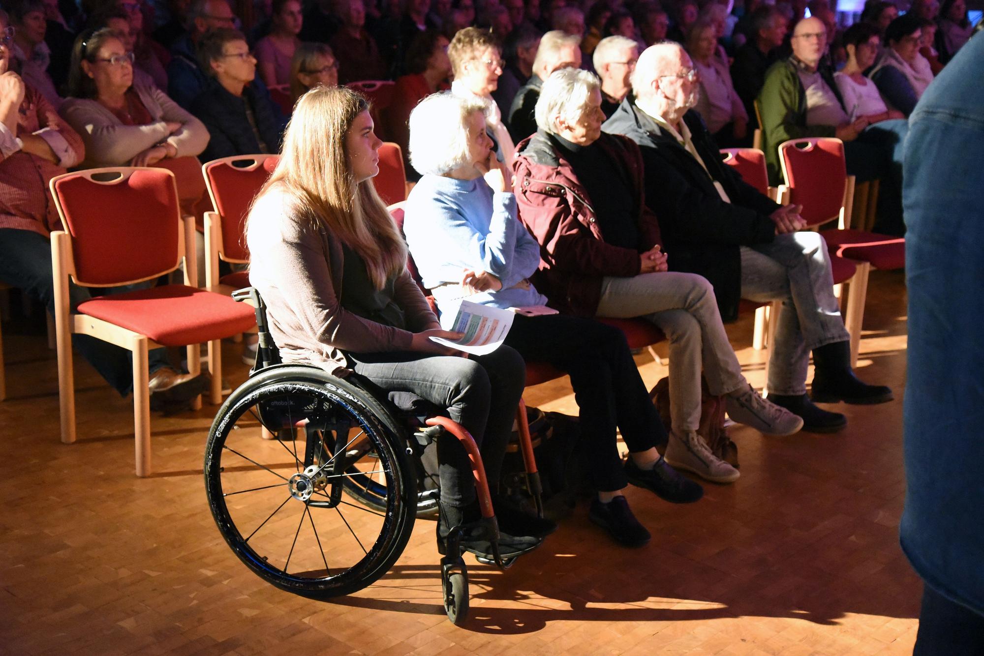 Eine Frau im Rollstuhl sitzt mit weiteren Menschen in der Christuskirche.