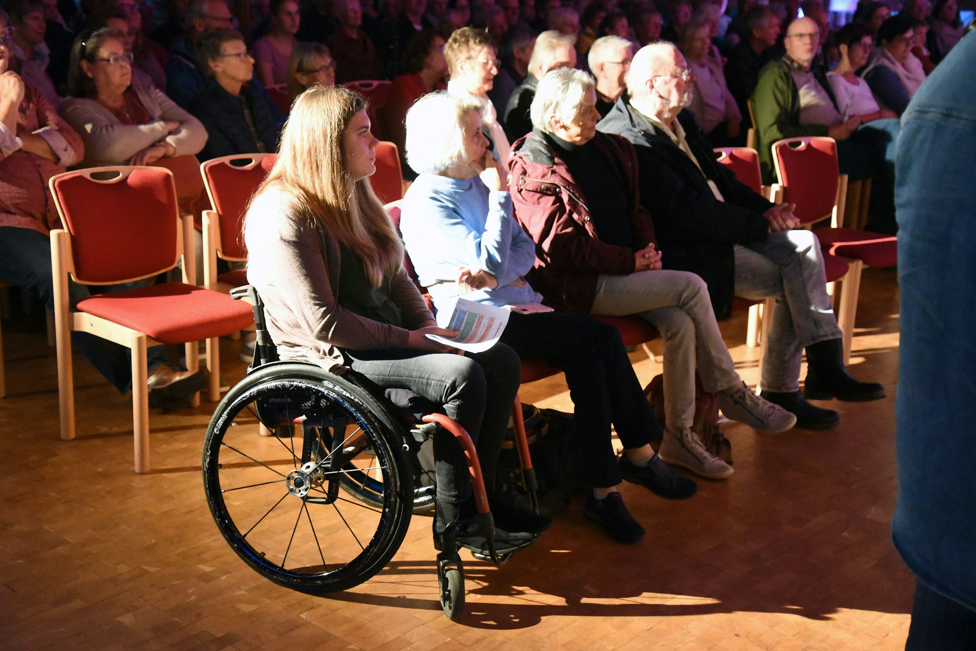 Eine Frau im Rollstuhl sitzt mit weiteren Menschen in der Christuskirche.