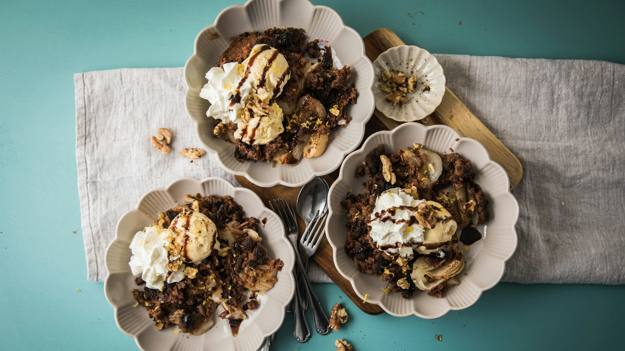 Drei Schüsseln mit Birnen-Schokoladen-Crumble stehen auf einem Tisch.