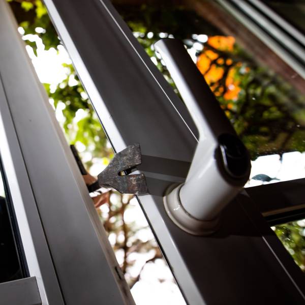 Ein vermummter Mann bricht in der gestellten Szene ein Fenster auf.