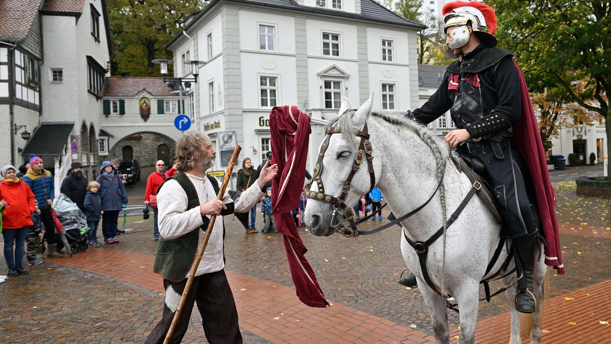 Ein als St. Martin verkleideter Schauspieler teilt seinen Mantel mit einem als Bettler verkleideten Schauspieler.