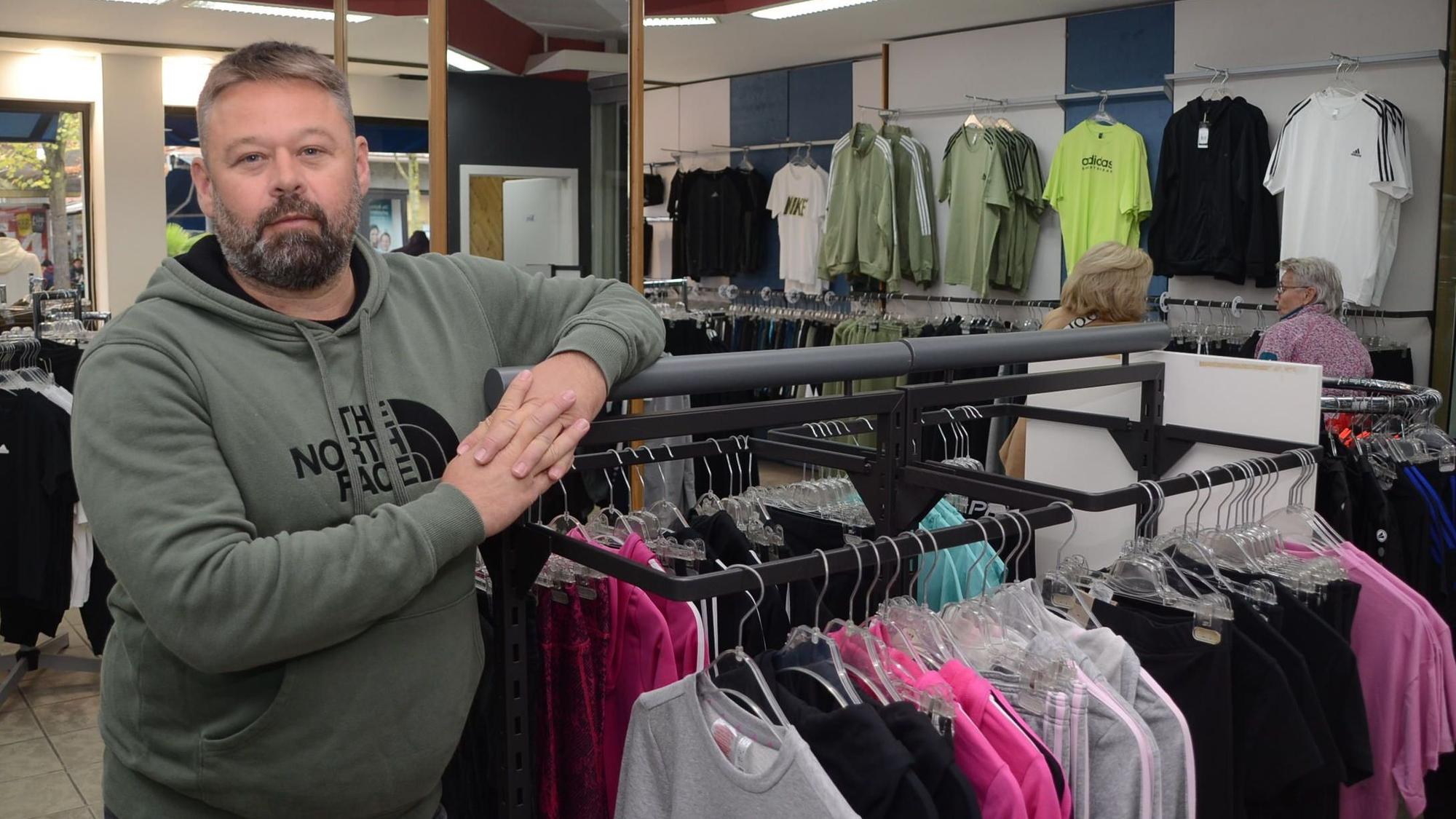 Ein Mann steht in einem Geschäft an einem Kleiderständer