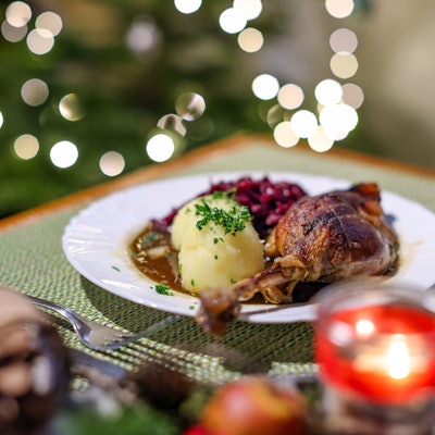 Eine Portion Gänsekeule mit Rotkraut und Klößen steht auf dem Tisch.