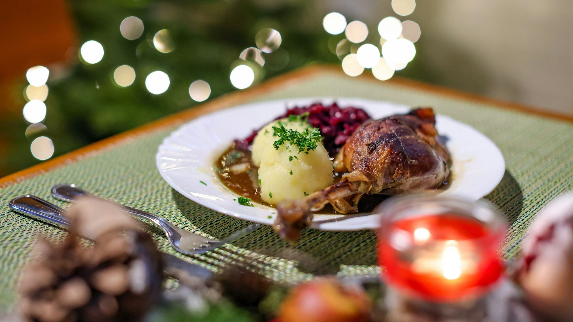 Eine Portion Gänsekeule mit Rotkraut und Klößen steht auf dem Tisch.